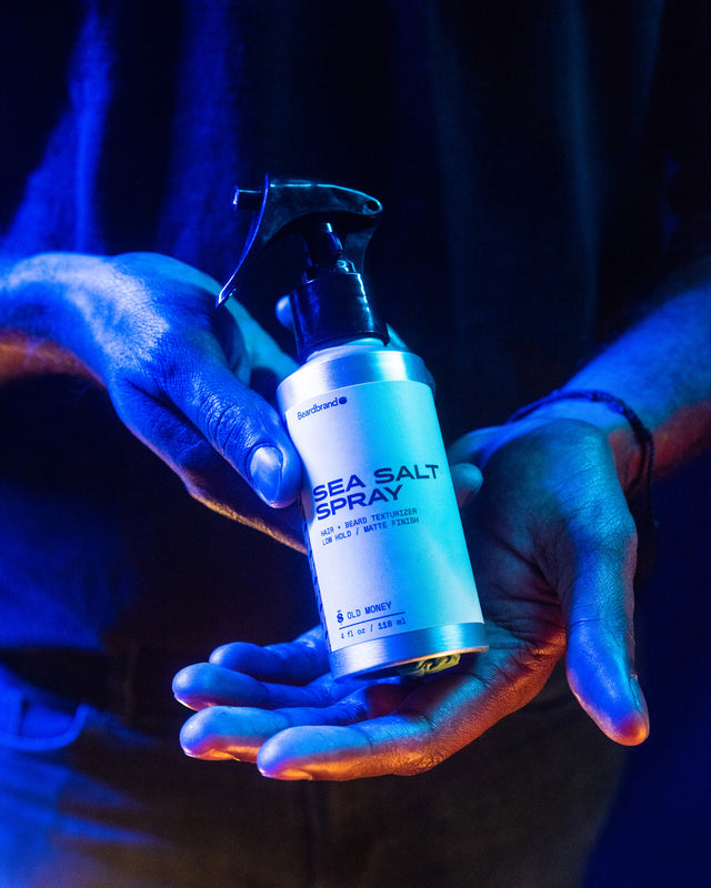 A person showing in their hands the front of Beardbrand Sea Salt Spray in vibrant lighting.