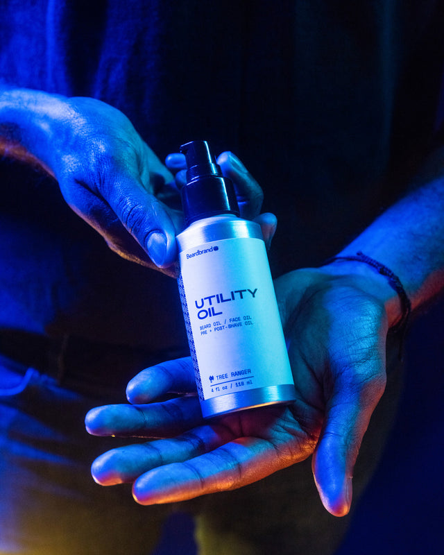 Beardbrand Utility Oil held in a person's hands in vibrant lighting.