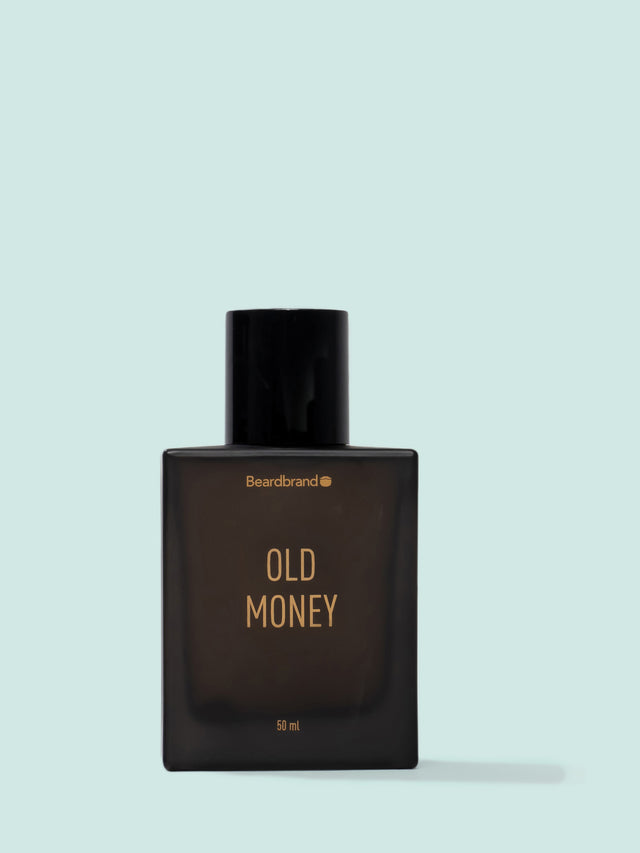 An amber colored bottle of Beardbrand Old Money Eau de Parfum on a striking blue backdrop.