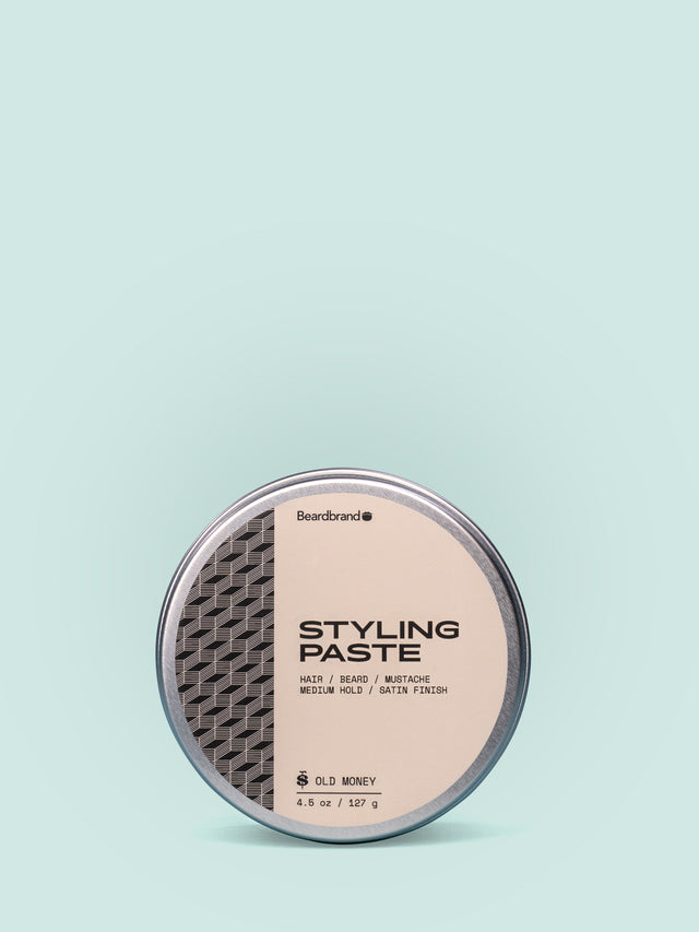 Beardbrand Styling Paste in Aluminum tin against a striking light blue background.