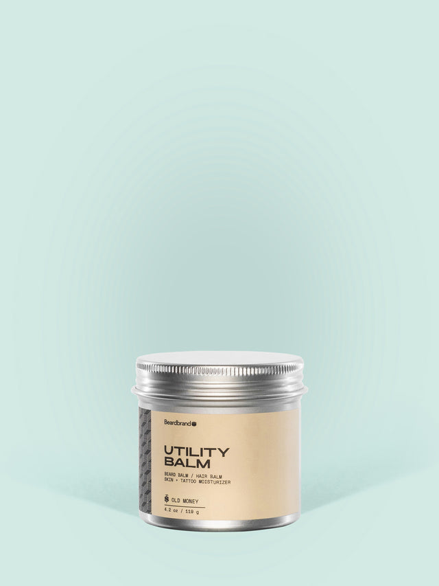 Beardbrand Utility Balm in an aluminum jar against a light blue background.