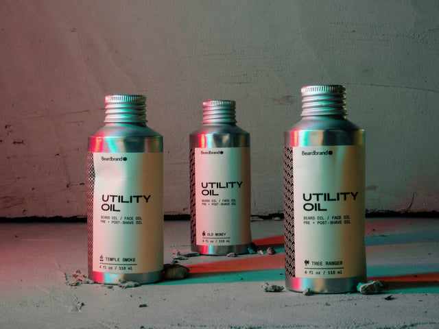 3 bottles of Utility Oil showing off their dents on a concrete background with red and blue lighting.