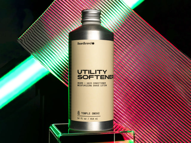 Utility Softener in aluminum packaging against a teal and magenta neon backdrop.